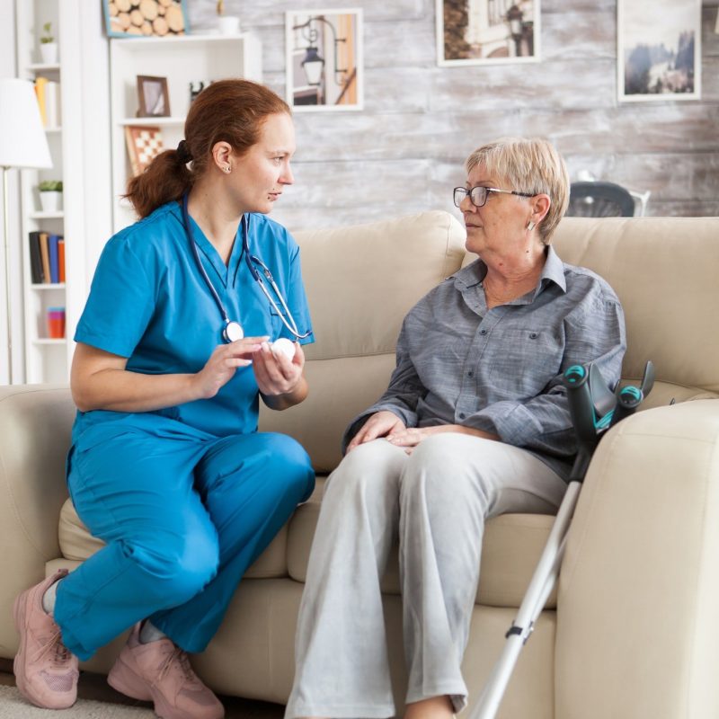 female-nurse-sitting-on-couch-with-senior-woman.jpg