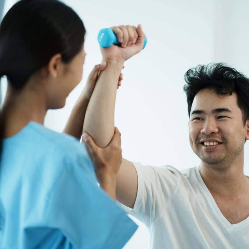 Physiotherapist treating rehabilitation arm pain patient doing physical therapy exercises.